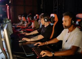 Młodzi gracze e-sportowi rywalizują przy komputerach w hali turniejowej