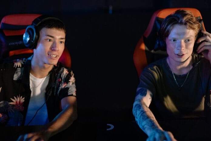 Dwóch młodych mężczyzn gra w turnieju e-sportowym w ciemnym pokoju