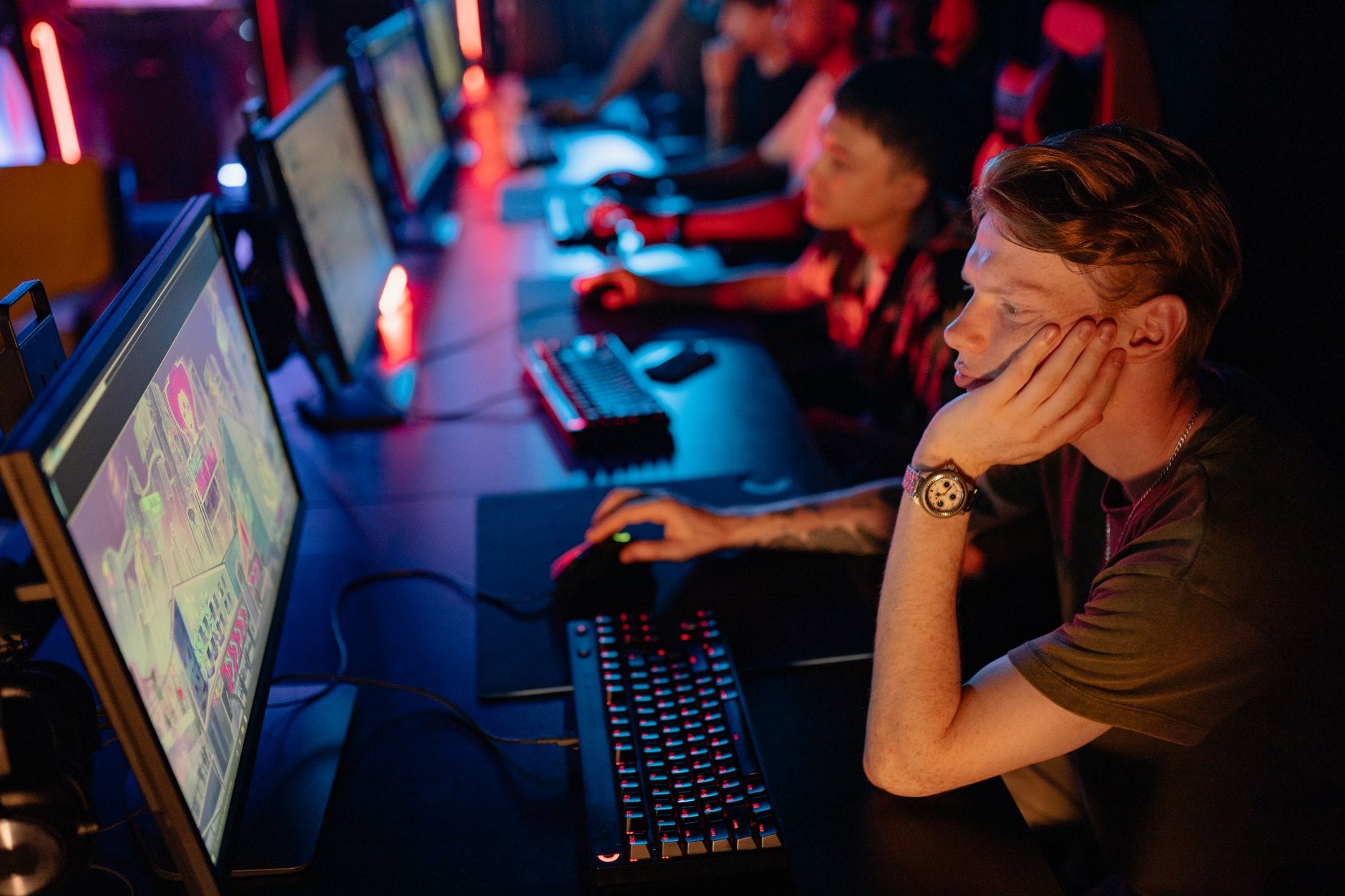 Zawodowi gracze e-sportowi skupieni przy komputerach w ciemnej hali