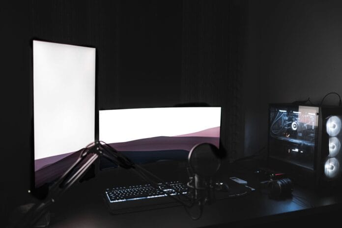 Stanowisko gamingowe z podświetlanymi monitorami, mikrofonem i PC w ciemnym poko Stanowisko gamingowe z podświetlanymi monitorami, mikrofonem i PC w ciemnym poko