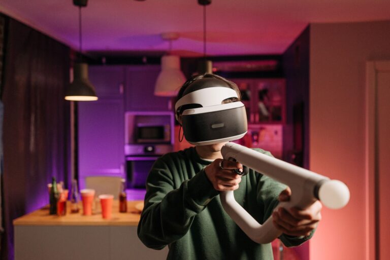 Osoba w goglach VR grająca kontrolerem w ciemnym pokoju
